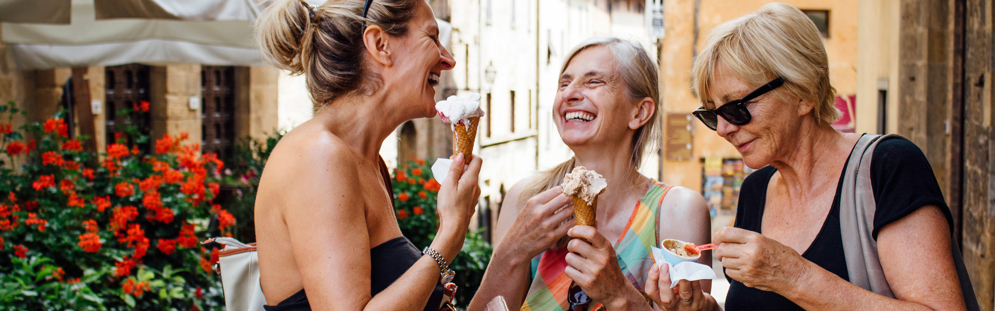 Three happy women eating icecream in town.