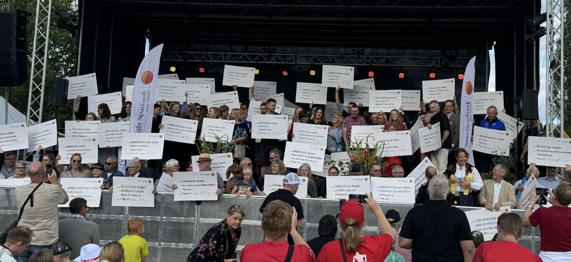 Människor som står på en scen och tar emot stora checkar. 