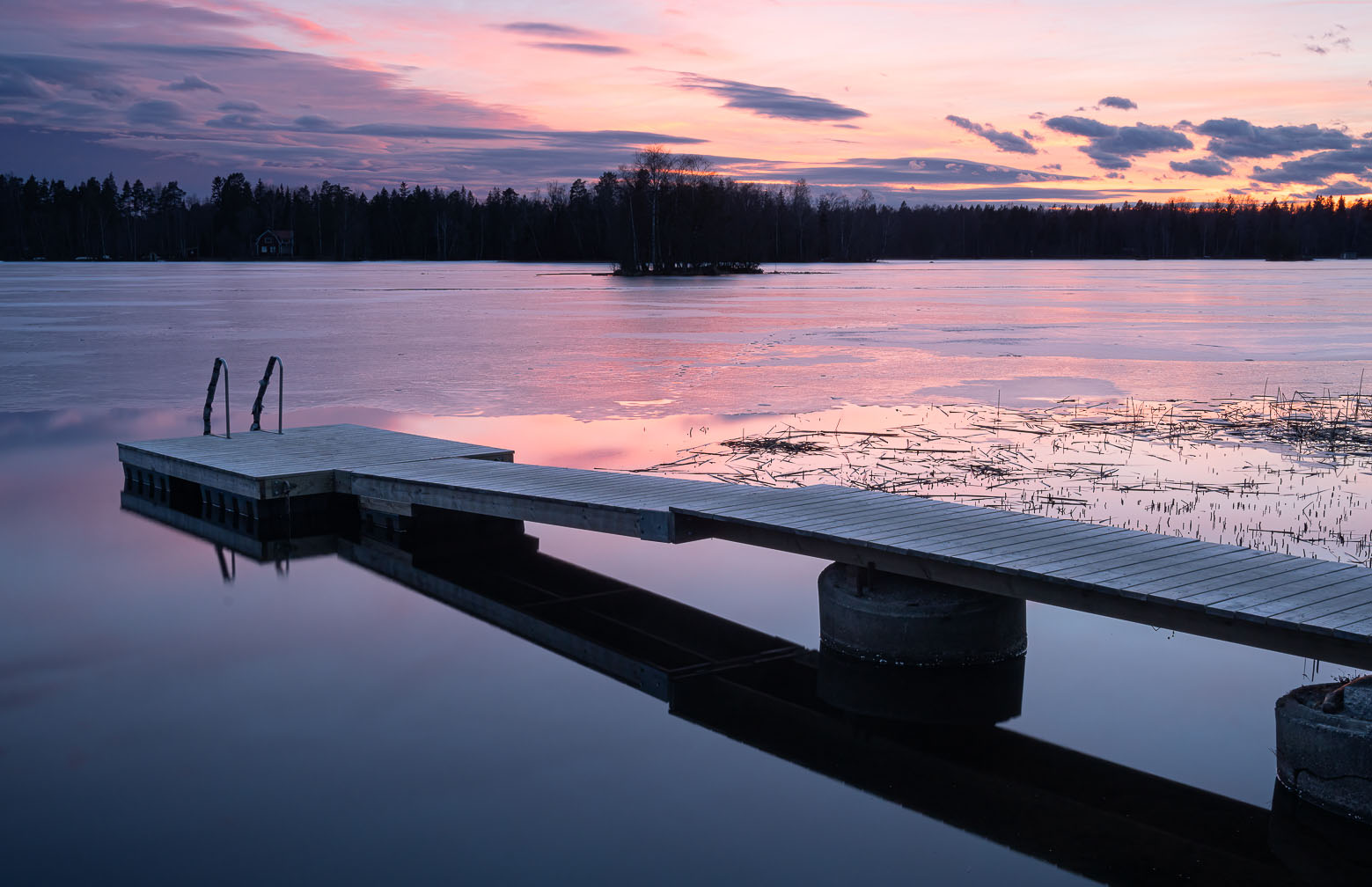 En sjö med tunn is och en brygga. 