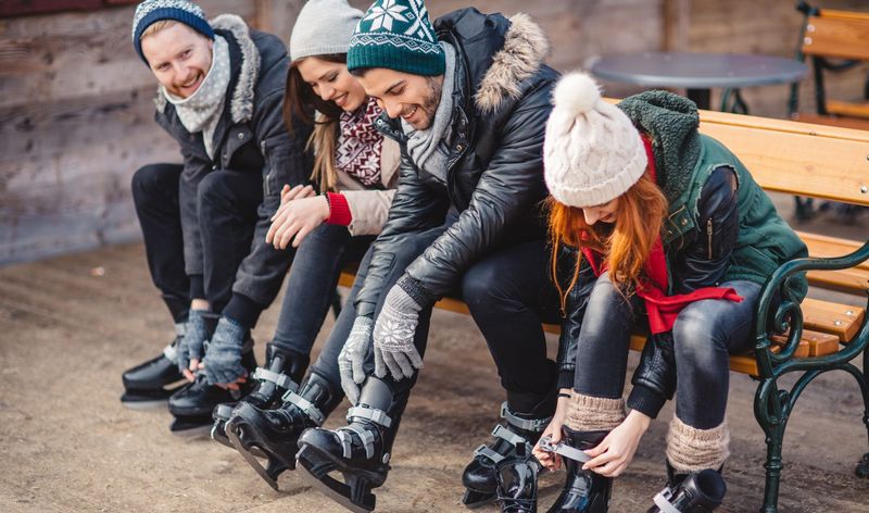 People sitting on a bench putting on skates 